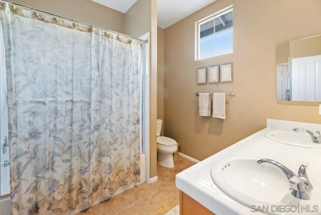 14268 Silver Ridge Road Poway, CA 92064 - Photo 48 of 53 a bathroom with a sink a toilet and shower curtain