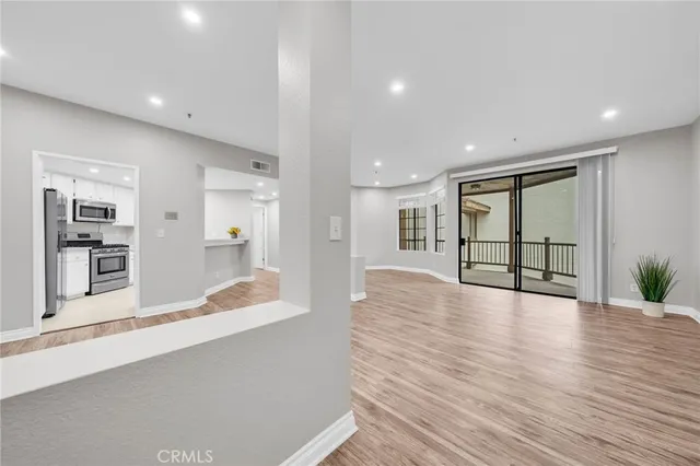 a view of an empty room with wooden floor and a large window