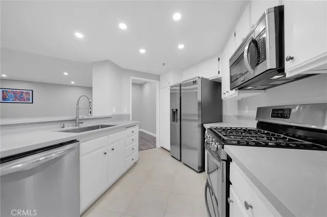 a kitchen with stainless steel appliances a sink a stove a refrigerator and cabinets