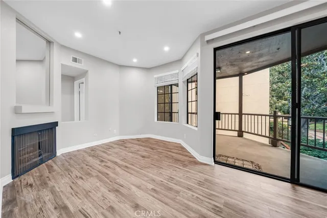 a view of empty room with wooden floor and fireplace