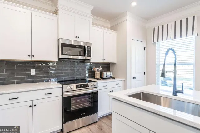a kitchen with granite countertop white cabinets and white appliances