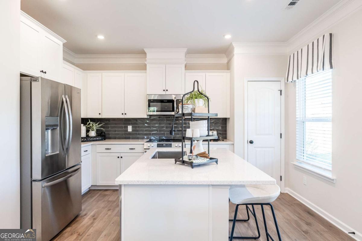 10413 Trellis Lane, Unit (LOT 33) Hampton, GA 30228 - Photo 19 of 39 a kitchen that has a kitchen island wooden cabinets and stainless steel appliances