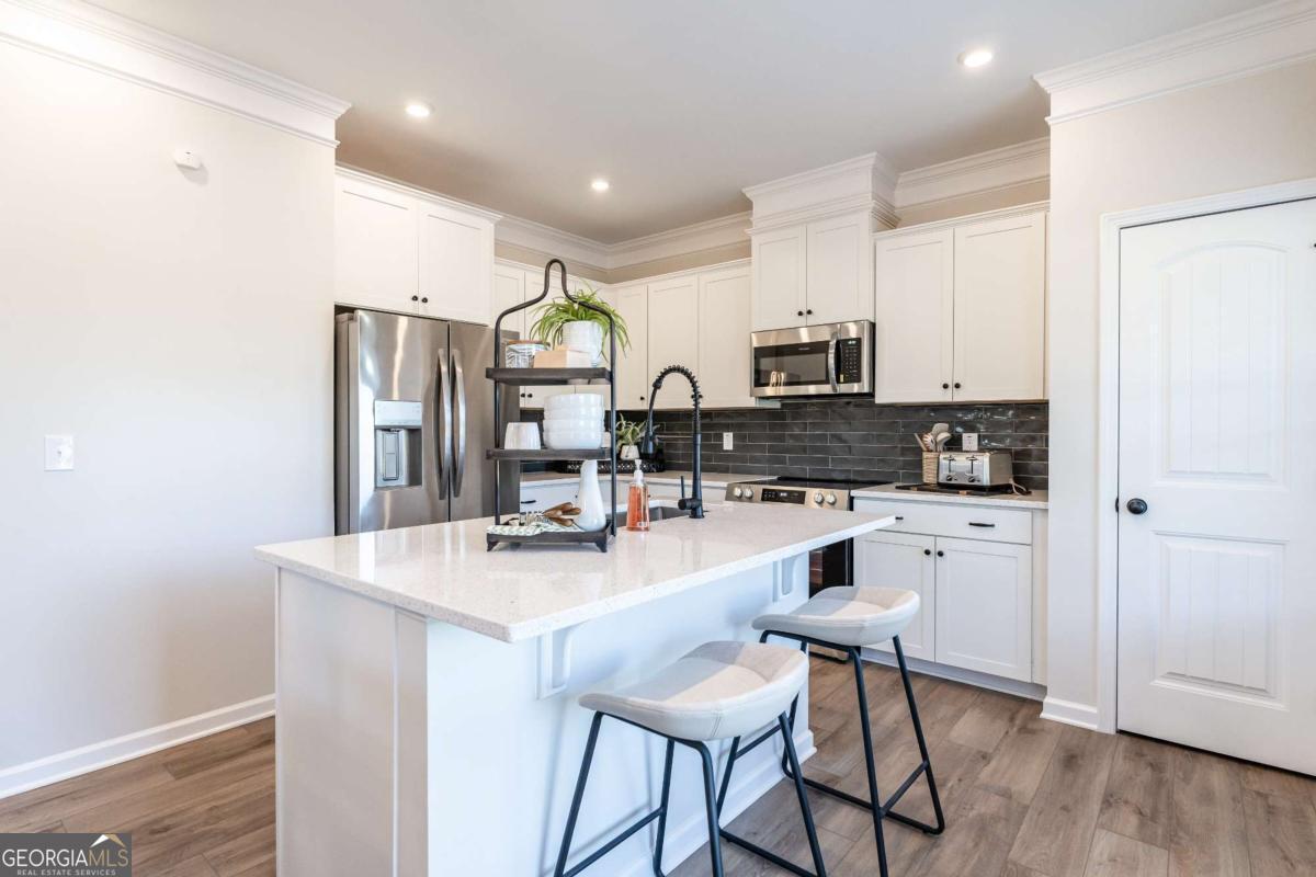 10413 Trellis Lane, Unit (LOT 33) Hampton, GA 30228 - Photo 20 of 39 a kitchen with stainless steel appliances granite countertop a stove a sink a refrigerator a microwave oven with white cabinets and wooden floor