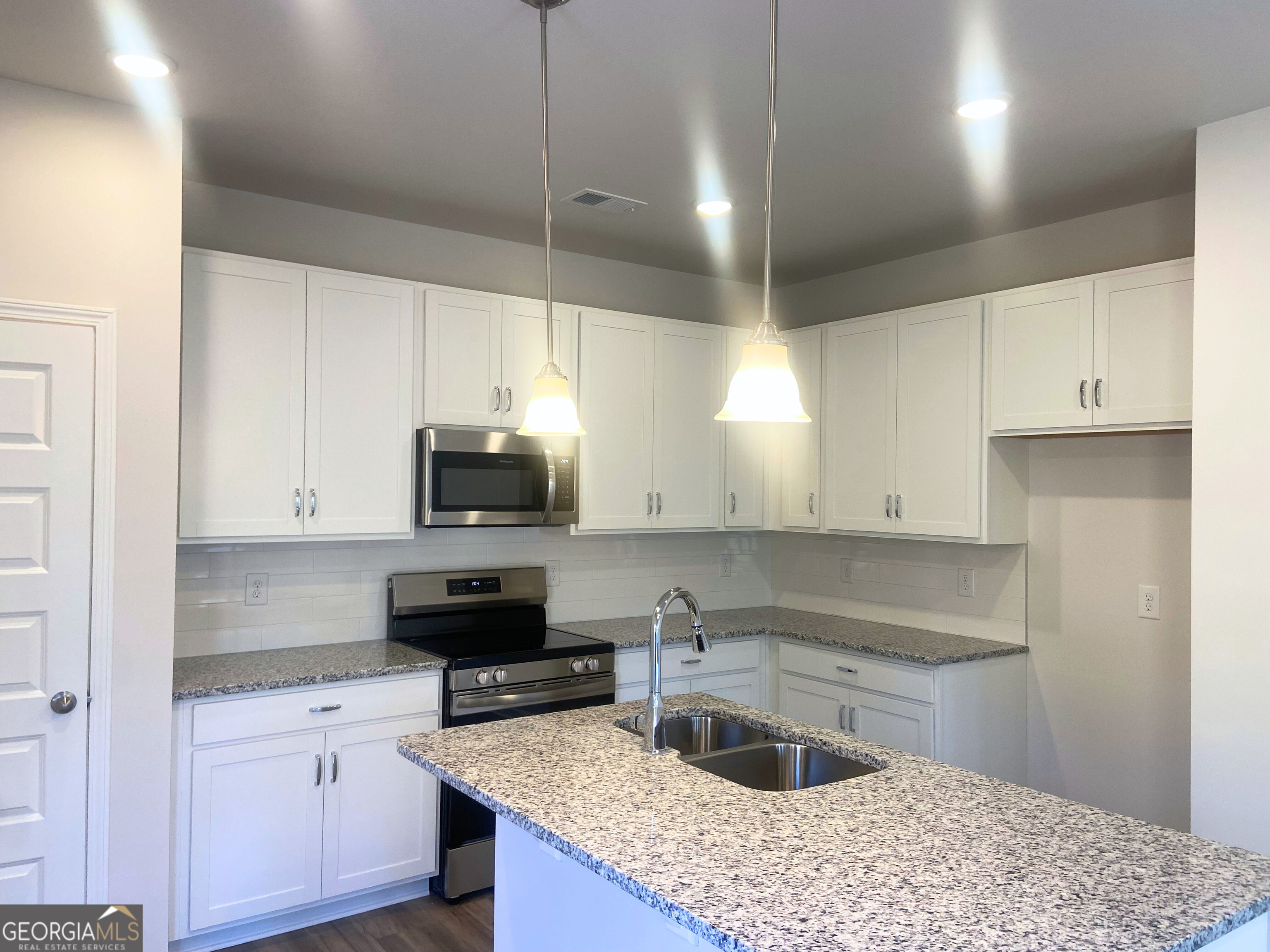 10413 Trellis Lane, Unit (LOT 33) Hampton, GA 30228 - Photo 4 of 39 a kitchen with granite countertop a sink a stove and cabinets