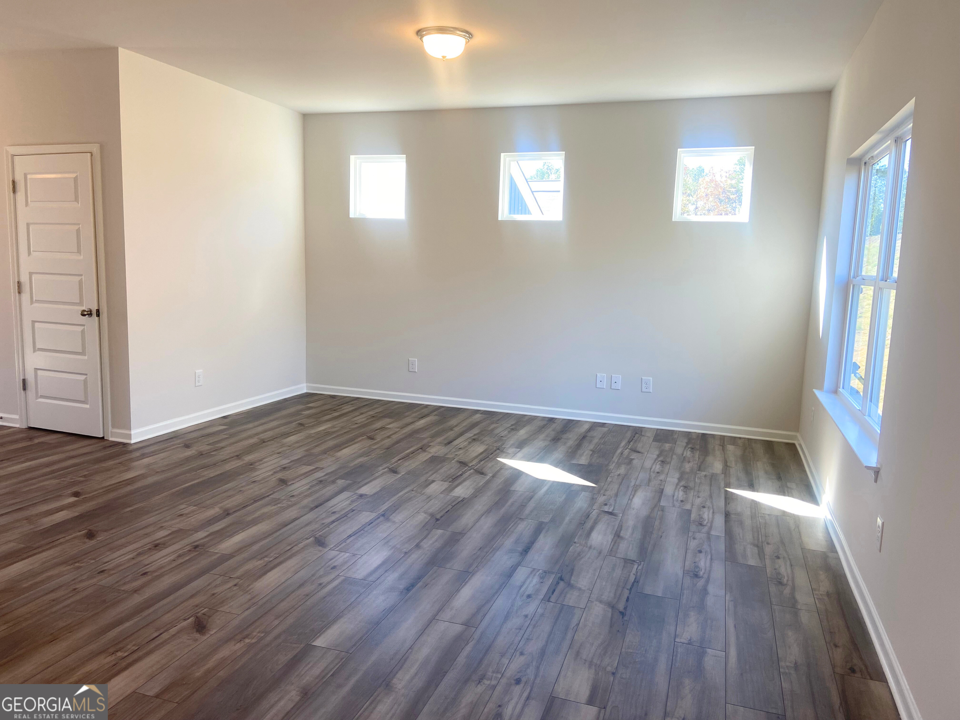 10413 Trellis Lane, Unit (LOT 33) Hampton, GA 30228 - Photo 5 of 39 an empty room with wooden floor and windows
