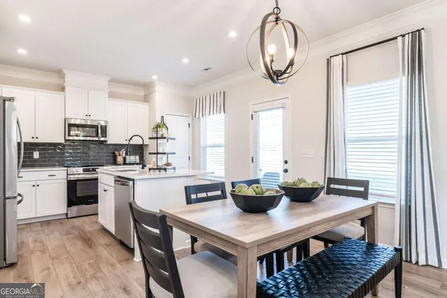 a kitchen with stainless steel appliances a table chairs and a window