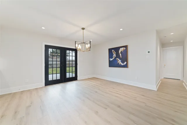 a view of an empty room with window and wooden floor