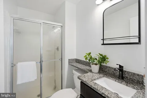 a bathroom with a granite countertop sink a toilet and a mirror