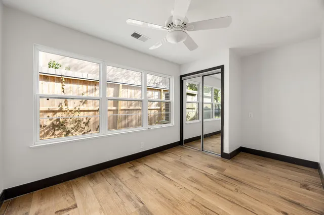 a view of an empty room with wooden floor and a window