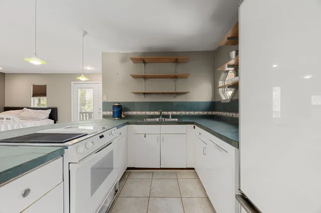 a kitchen with a sink dishwasher and white cabinets with wooden floor