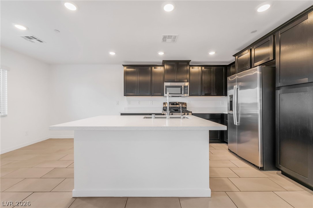 894 Cadence View Way Henderson, NV 89011 - Photo 7 of 23 Culinary delights await in this bright kitchen with a spacious island, modern appliances, and ample cabinet storage.
