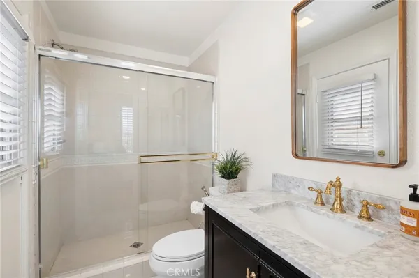 a bathroom with a granite countertop sink toilet a mirror a vanity and shower
