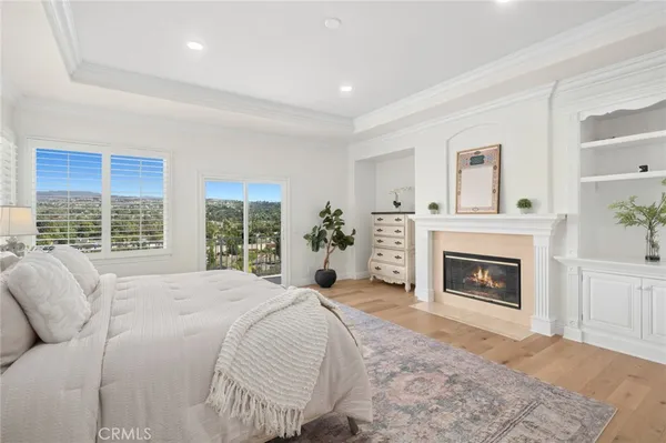 a bed sitting in a spacious bedroom next to a window and a fireplace