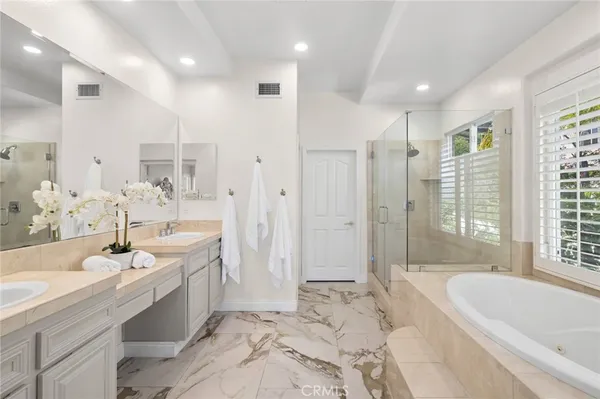 a spacious bathroom with a tub sink shower and mirror