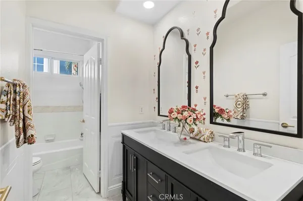 a bathroom with a double vanity sink a mirror and a bathtub