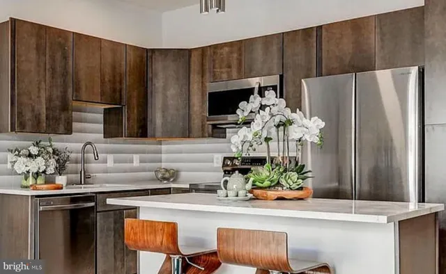 a kitchen with stainless steel appliances granite countertop a dining table and chairs