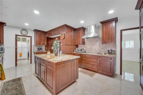 a kitchen with kitchen island granite countertop a sink and refrigerator