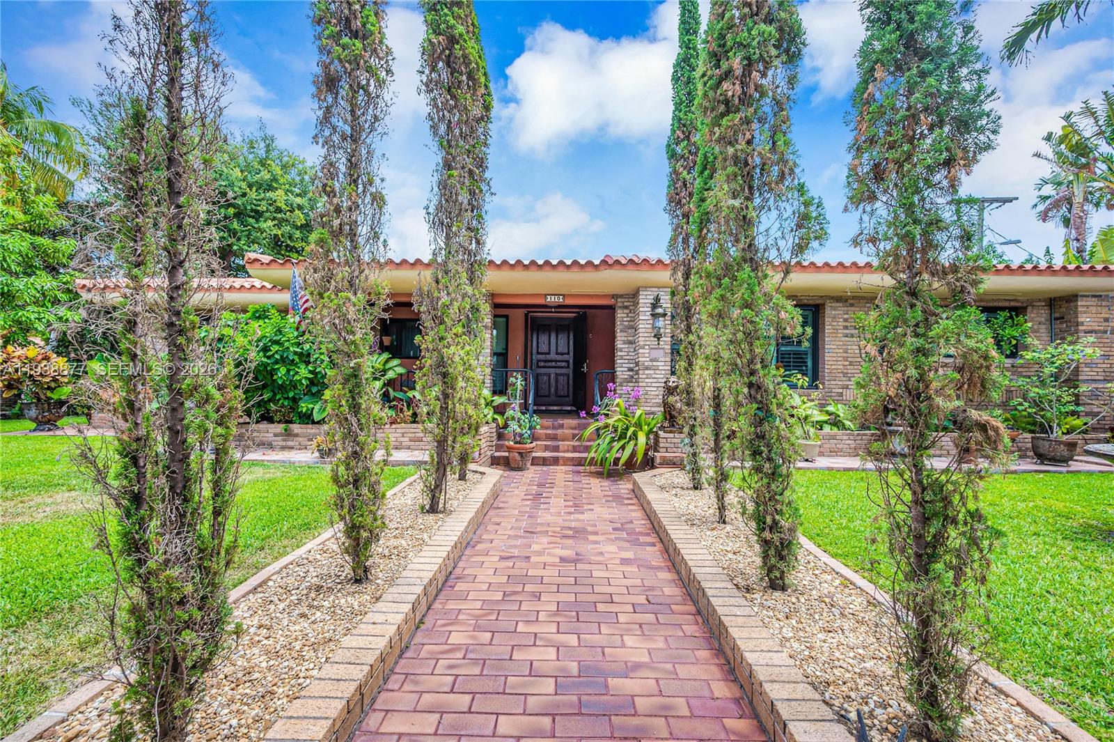 110 Shore Drive West Miami, FL 33133 - Photo 3 of 40 a front view of a house with a yard and potted plants