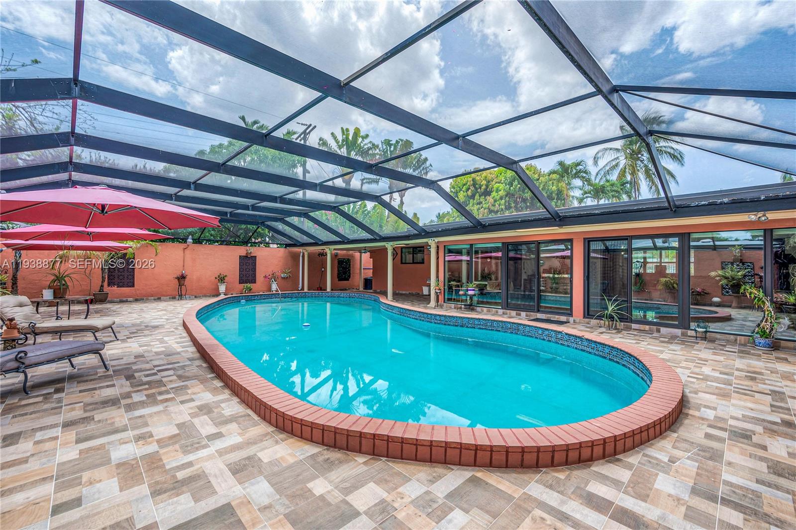 110 Shore Drive West Miami, FL 33133 - Photo 9 of 40 a view of a swimming pool with a dining table and chairs under an umbrella