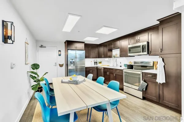 a kitchen with stainless steel appliances kitchen island granite countertop a refrigerator a stove a sink dishwasher and white cabinets with wooden floor