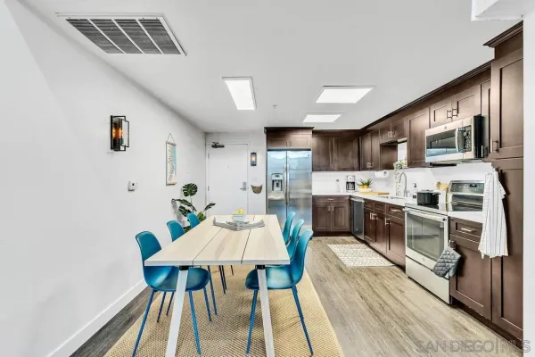 a open kitchen with stainless steel appliances kitchen island granite countertop a stove a sink dishwasher and white cabinets with wooden floor