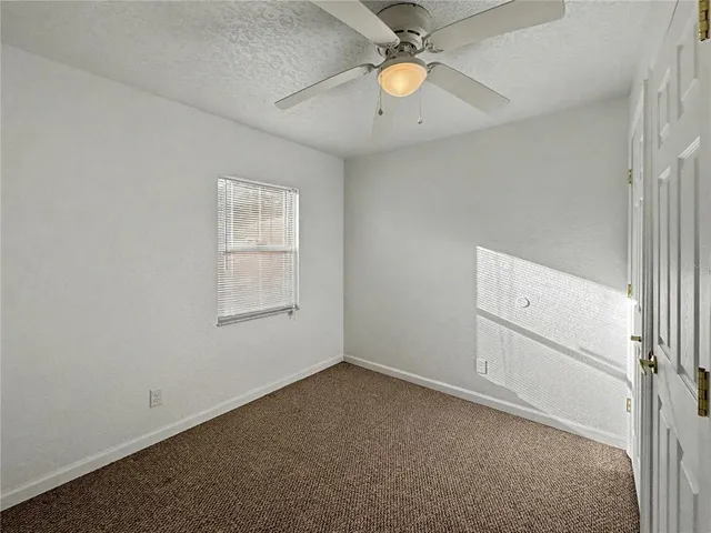 an empty room with a window and a ceiling fan