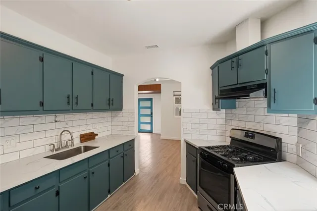 a kitchen with stainless steel appliances a sink stove and cabinets
