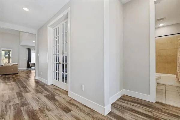 a view of a hallway with wooden floor and a bathroom