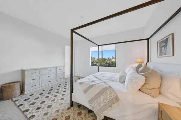 a bedroom with a bed and a lamp on the dresser