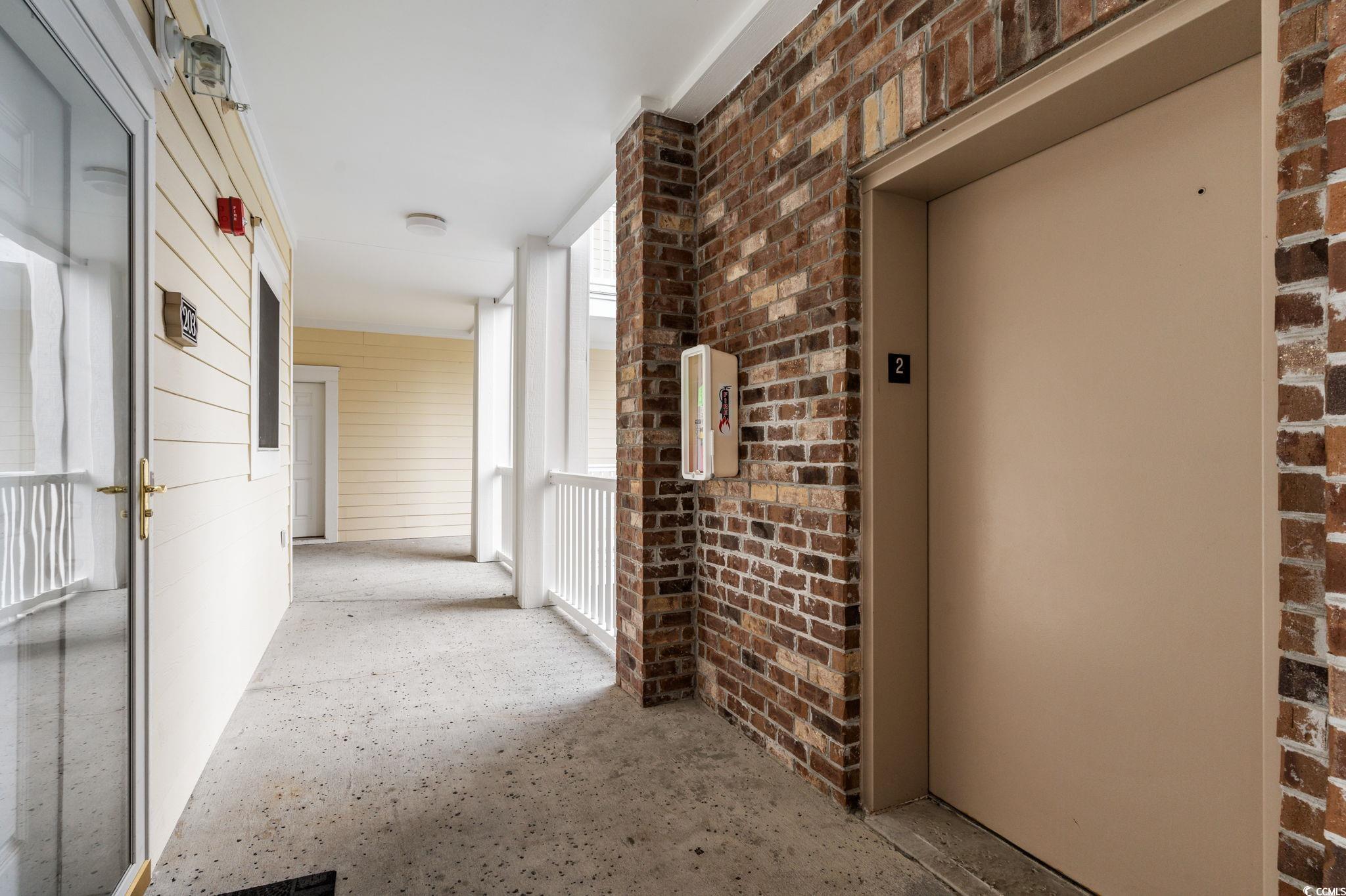 4843 Luster Leaf Circle, Unit 204 Myrtle Beach, SC 29577 - Photo 25 of 36 Corridor with elevator and brick wall