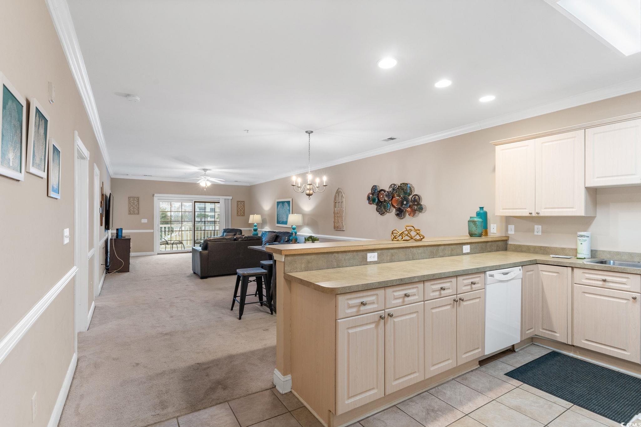 4843 Luster Leaf Circle, Unit 204 Myrtle Beach, SC 29577 - Photo 36 of 36 Kitchen featuring light colored carpet, light countertops, open floor plan, a peninsula, and hanging light fixtures