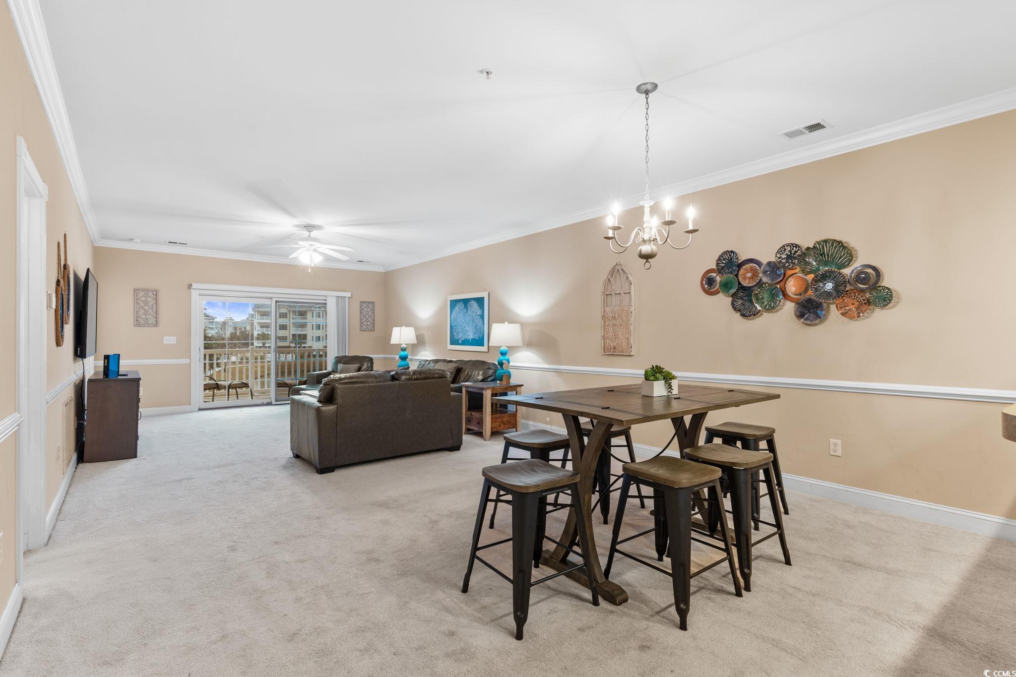 4843 Luster Leaf Circle, Unit 204 Myrtle Beach, SC 29577 - Photo 6 of 36 Dining space featuring light colored carpet, crown molding, ceiling fan, and a chandelier