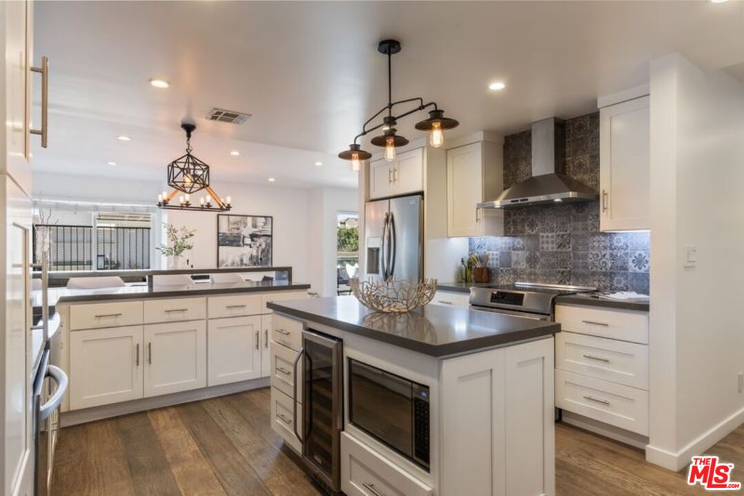 4300 Vía Dolce, Unit 102 Marina del Rey, CA 90292 - Photo 17 of 39 a kitchen with stainless steel appliances granite countertop a sink stove a refrigerator and white cabinets with wooden floor