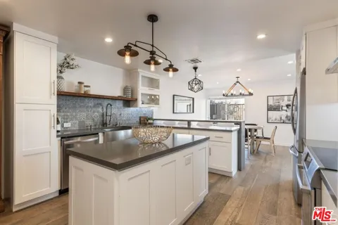 a kitchen with stainless steel appliances granite countertop a sink a stove a dining table and chairs with wooden floor