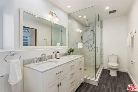 a bathroom with a double vanity sink toilet a mirror and shower