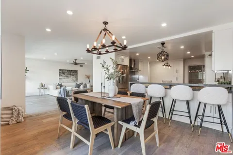 a view of a dining room and livingroom with furniture wooden floor a chandelier