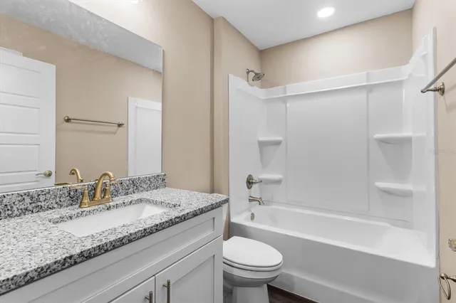 a bathroom with a granite countertop sink a toilet and shower