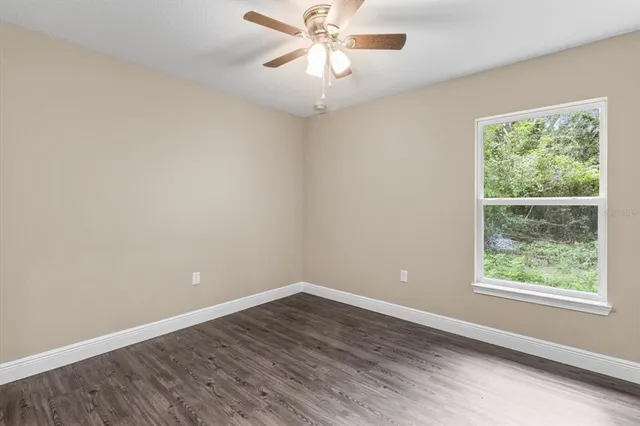 an empty room with a window and a fan