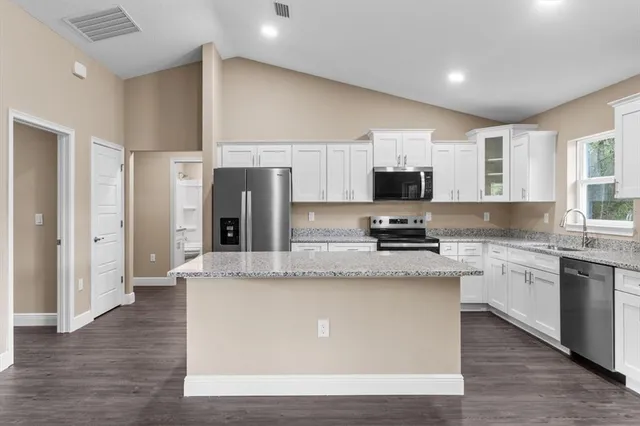 a large kitchen with stainless steel appliances granite countertop a stove a sink and a refrigerator