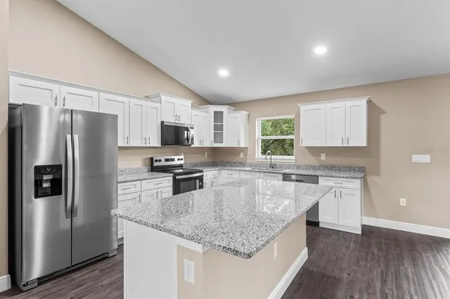 a kitchen with stainless steel appliances granite countertop a sink stove microwave and refrigerator