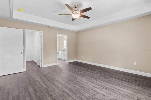 an empty room with wooden floor and a ceiling fan