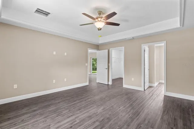 an empty room with wooden floor and ceiling fan