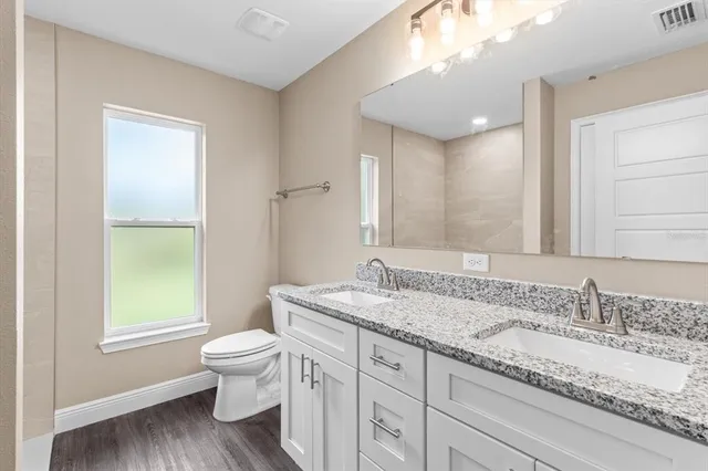 a bathroom with a granite countertop toilet a sink and a mirror