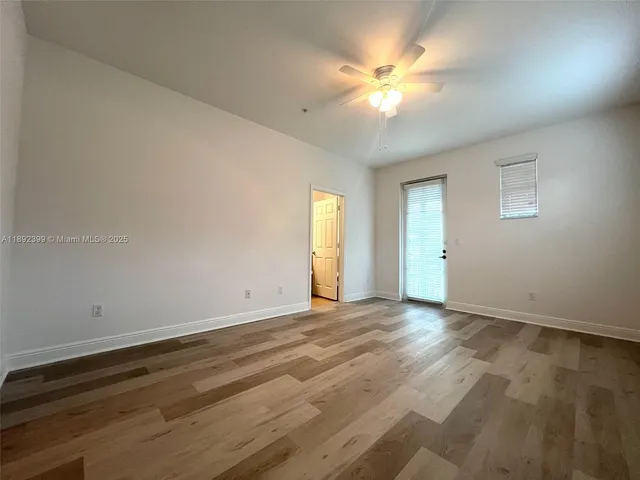 a view of an empty room with window and wooden floor