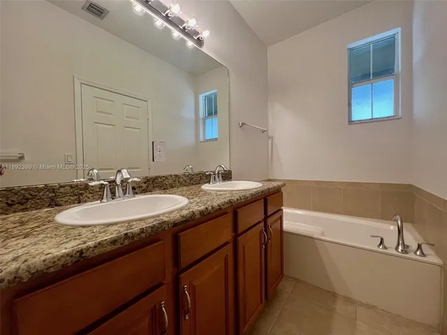 a bathroom with a granite countertop bathtub sink double and mirror