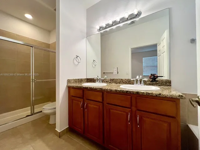 a bathroom with a granite countertop sink a toilet a mirror and shower