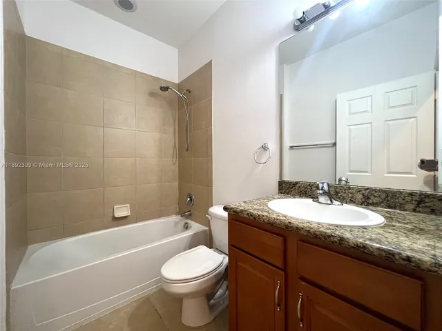 a bathroom with a granite countertop sink toilet mirror and bathtub