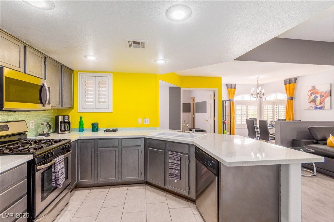 7400 West Flamingo Road, Unit 2006 Las Vegas, NV 89147 - Photo 30 of 30 Kitchen featuring appliances with stainless steel finishes, a peninsula, a chandelier, light countertops, and open floor plan