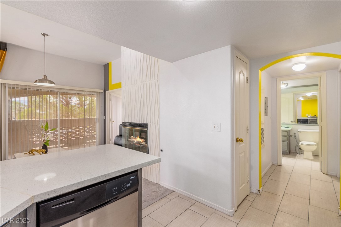 7400 West Flamingo Road, Unit 2006 Las Vegas, NV 89147 - Photo 15 of 30 Kitchen with stainless steel dishwasher, a large fireplace, arched walkways, light tile patterned floors, and decorative light fixtures