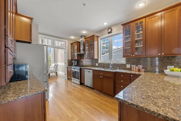 a large kitchen with stainless steel appliances granite countertop a large stove top oven a refrigerator a sink and dishwasher with wooden floor